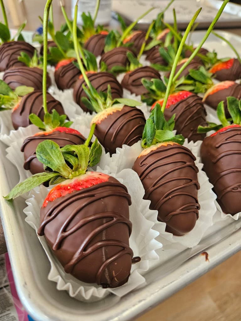 Chocolate-covered strawberries with a drizzle, lined in paper cups